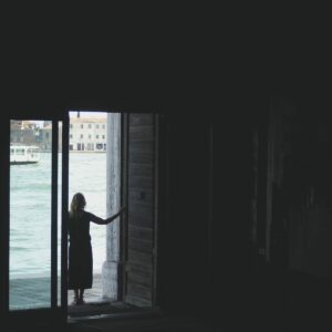 woman in black dress standing near window